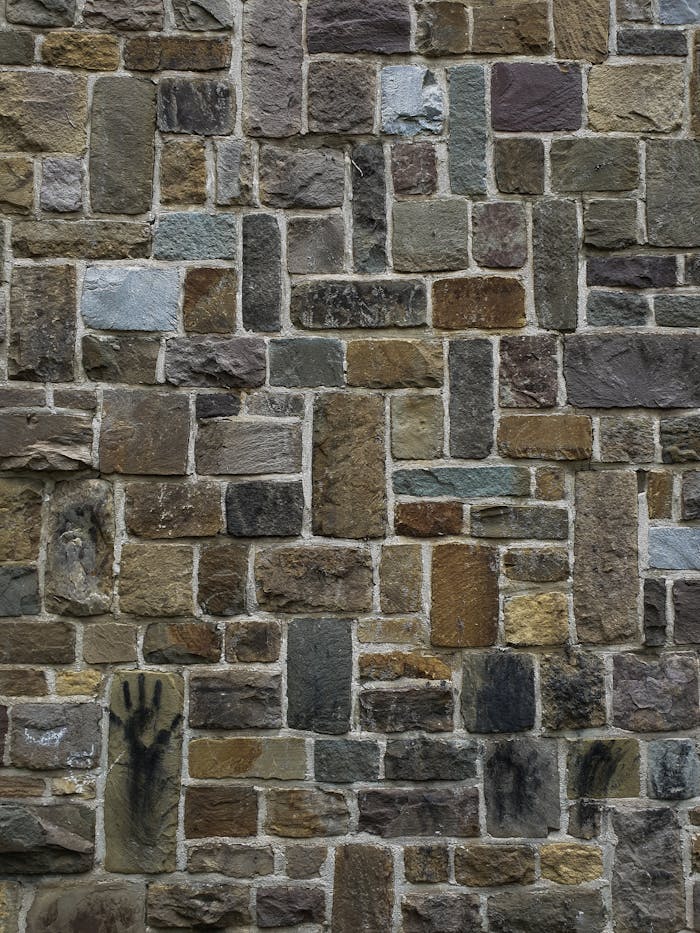 Close-up of an artistic stone wall with a handprint design.