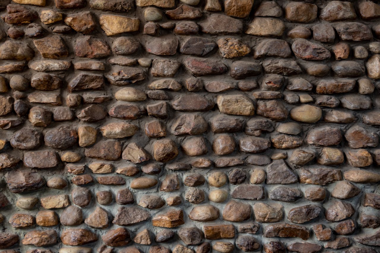 Textured rustic stone wall displaying a variety of natural stones in earthy tones.